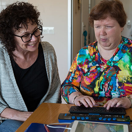 Client en begeleider werken samen met brailleregel