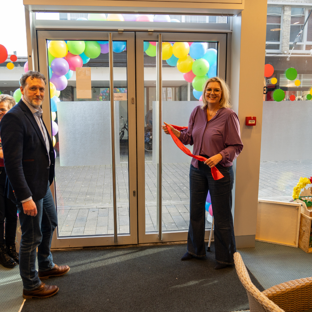 Wethouders Ivo Tillie en Yvonne Salvino staan bij de deur van Coppes Anders Gezien. Yvonne heeft het lint vast dat ze net hebben losgemaakt van de deur.