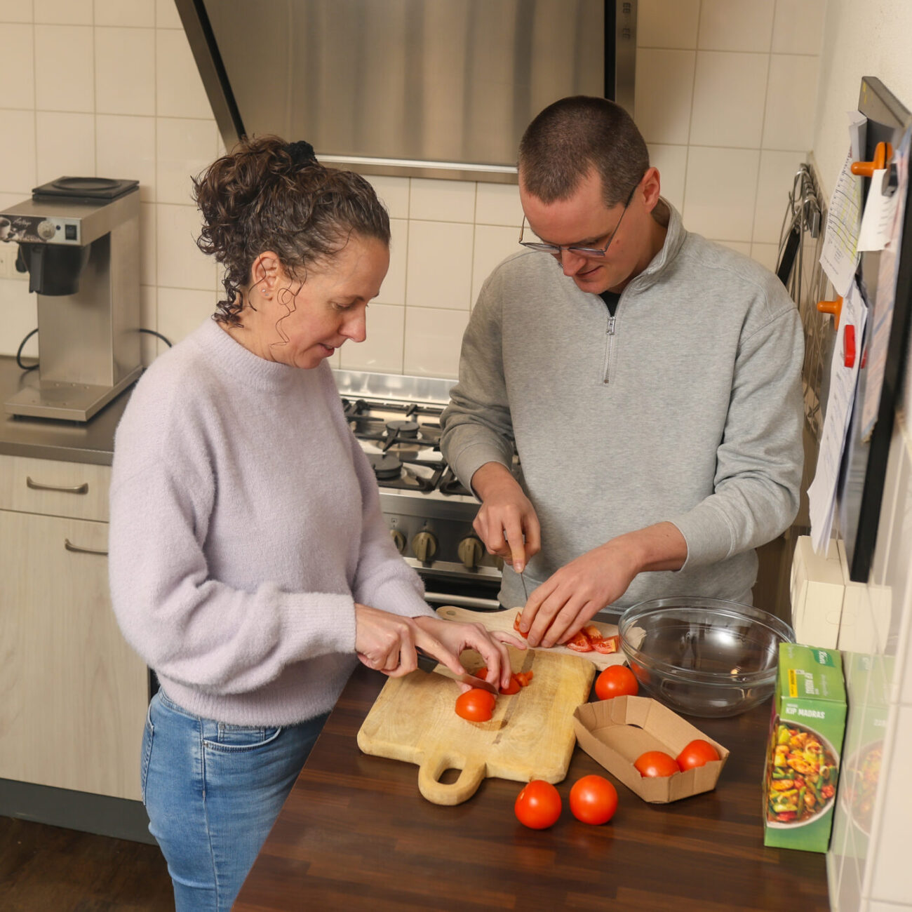 193 Een man en vrouw staan in de keuken en snijden samen tomaten op een snijplank.