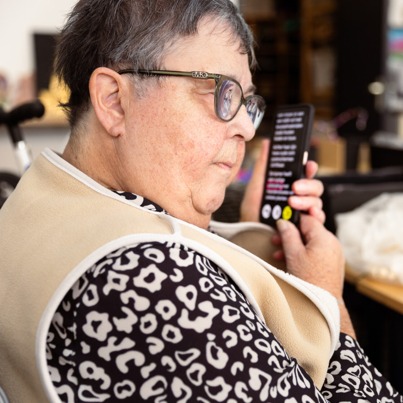 Een dame houdt haar telefoon naast haar oor en luistert naar wat er voorgelezen wordt.